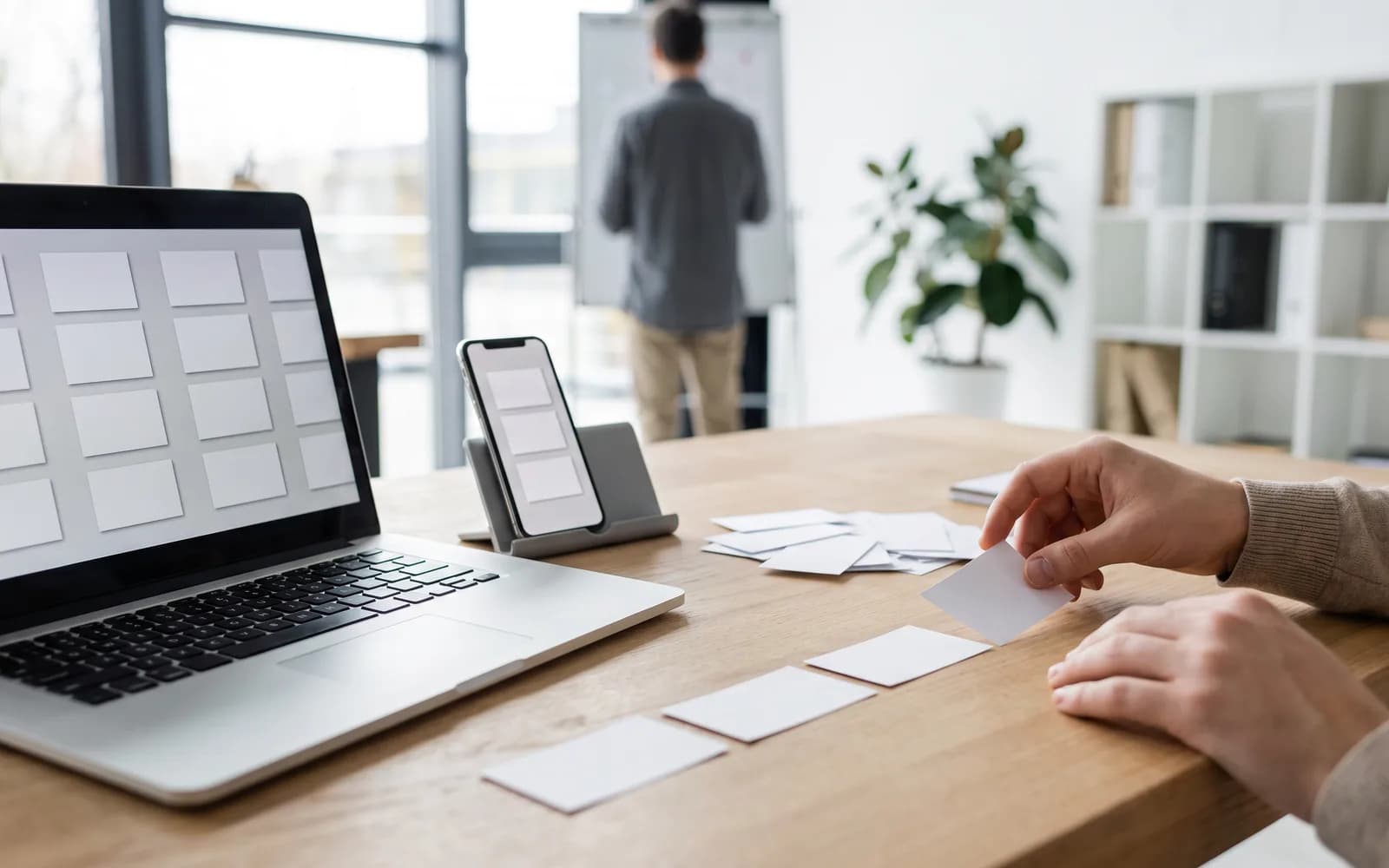 Bright workspace with laptop and smartphone, ordered task cards – work orchestration with Prakti
